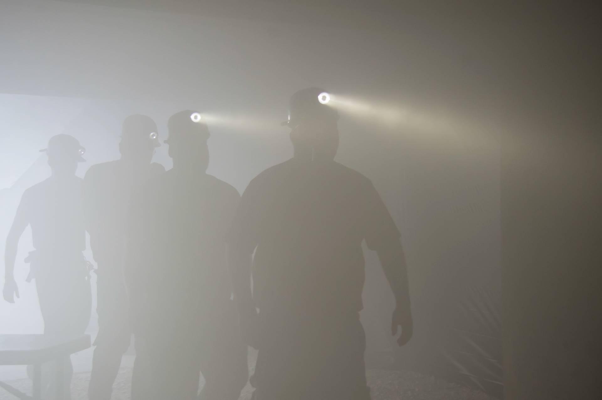 A group of miners in a dark area with their lights on